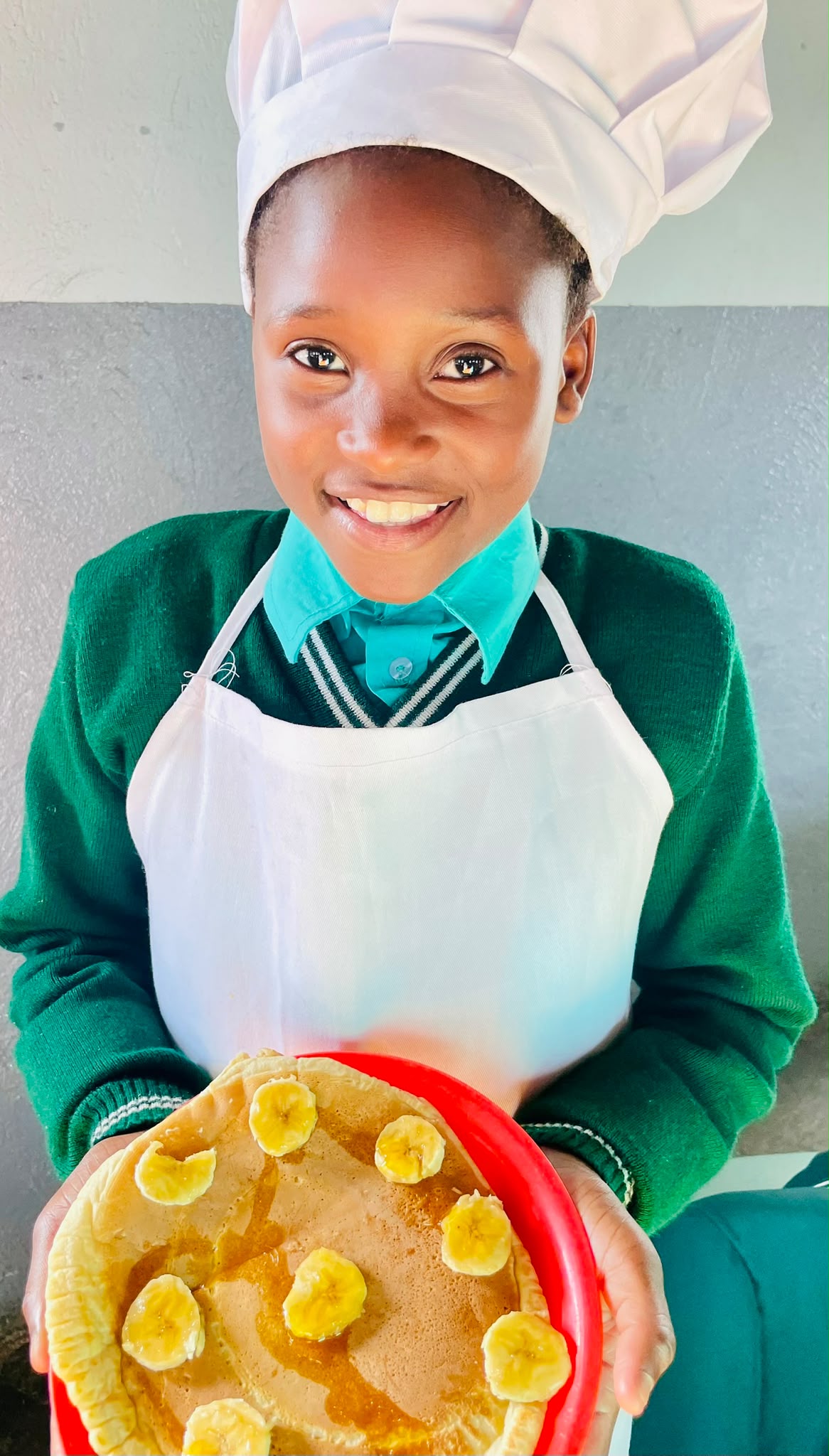 Pupil in a chef’s hat holding a pancake she made