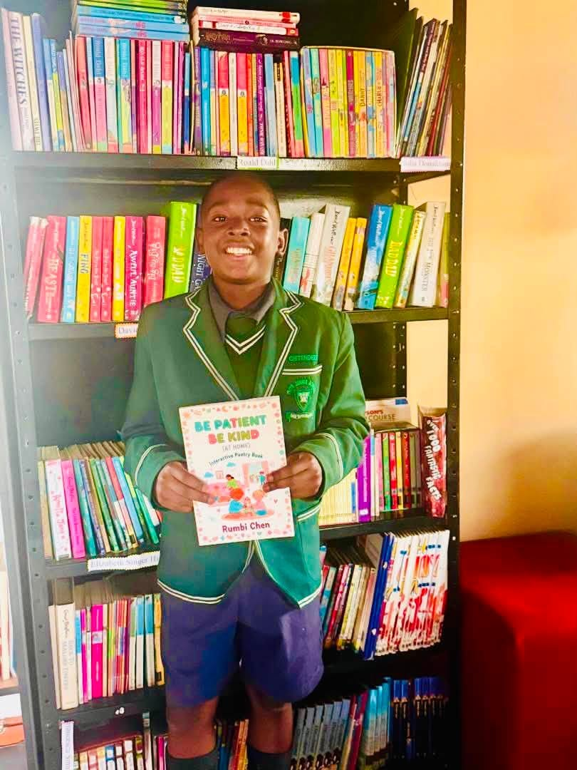 Pupil smiling with a poetry book in the school library