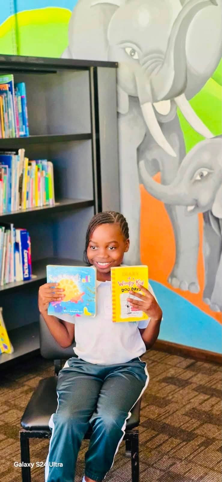 Pupil in the library holding two books